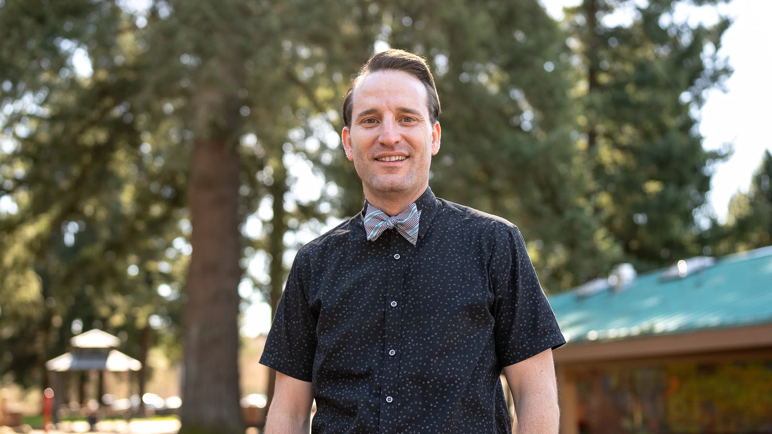 Physician Caleb Hentges standing in front of a building and tree